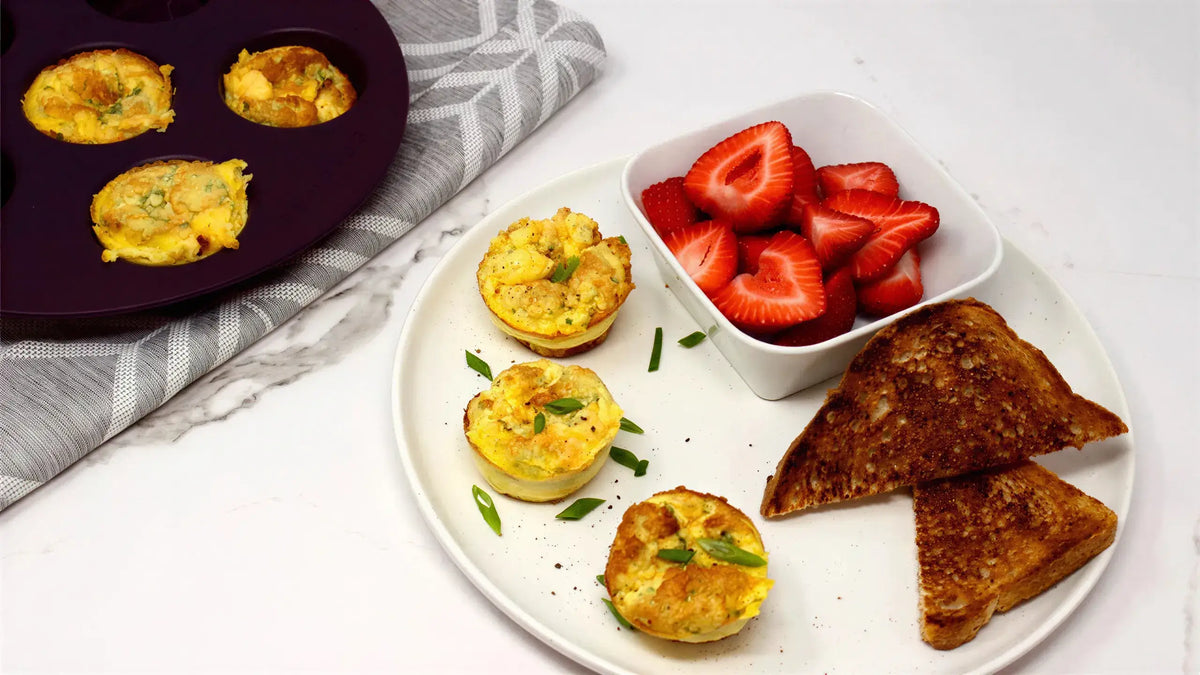 Plate with egg muffins baked with Epicure 3 Onion Dip Mix, toast, and strawberries on a white surface