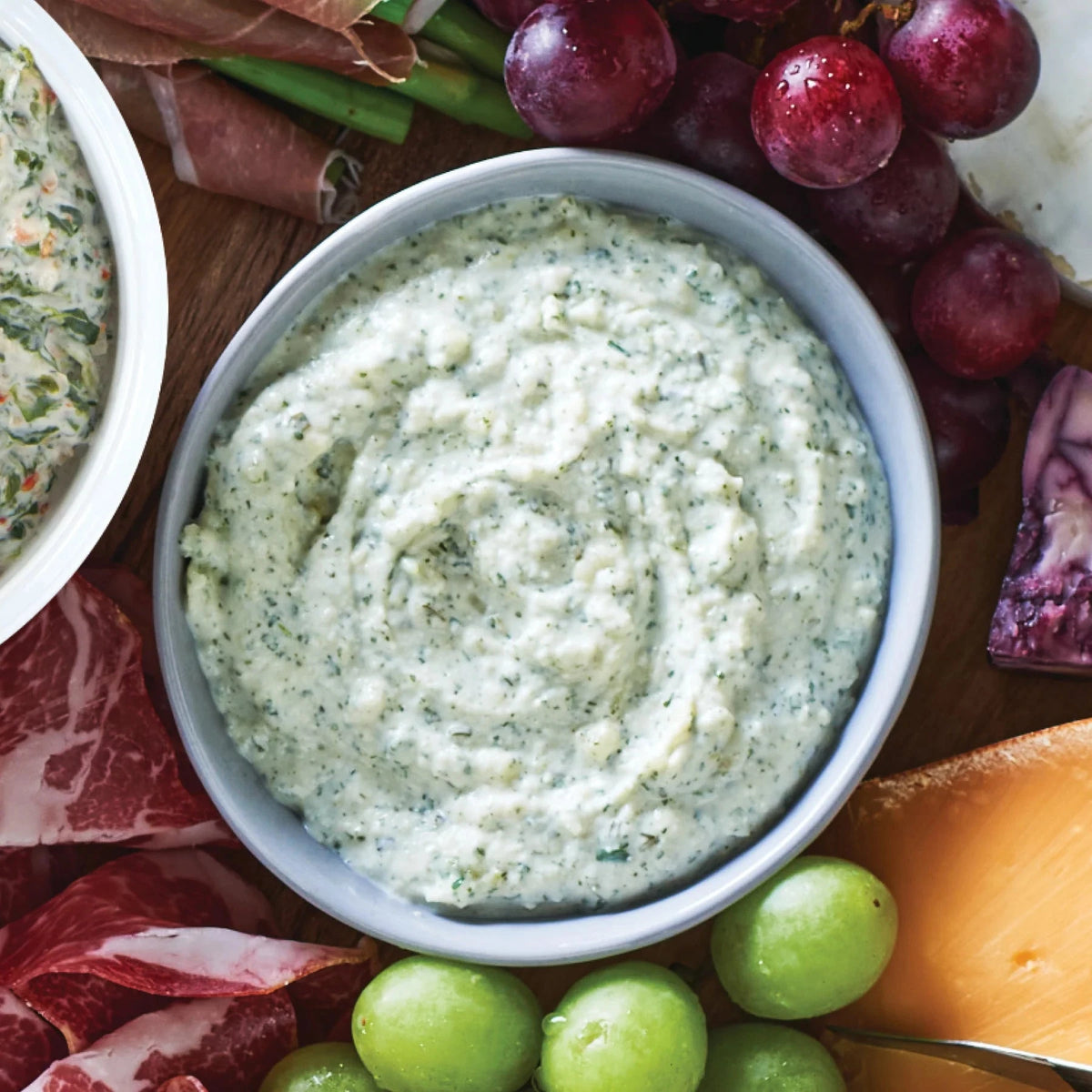 Bowl of Epicure 3 Onion Dip on a charcuterie board with fruits and meats