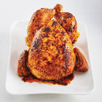 Air Fryer Rotisserie Chicken with crispy golden-brown skin and charred spots, served on a white rectangular plate against a light gray background.