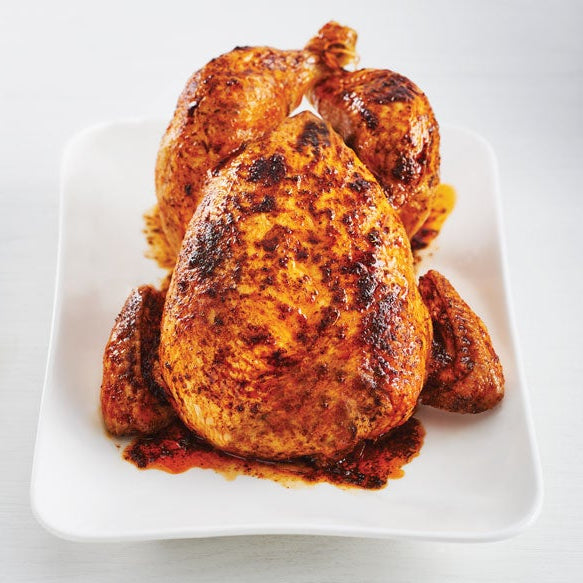 Air Fryer Rotisserie Chicken with crispy golden-brown skin and charred spots, served on a white rectangular plate against a light gray background.