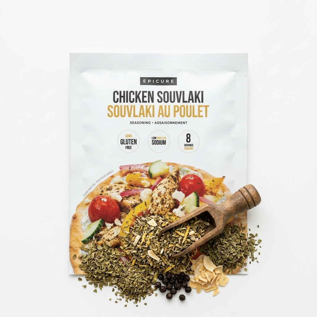 A package of Epicure Chicken Souvlaki seasoning mix, shown on a clean white background with the seasoning spilled out below in a wooden scoop and pile.