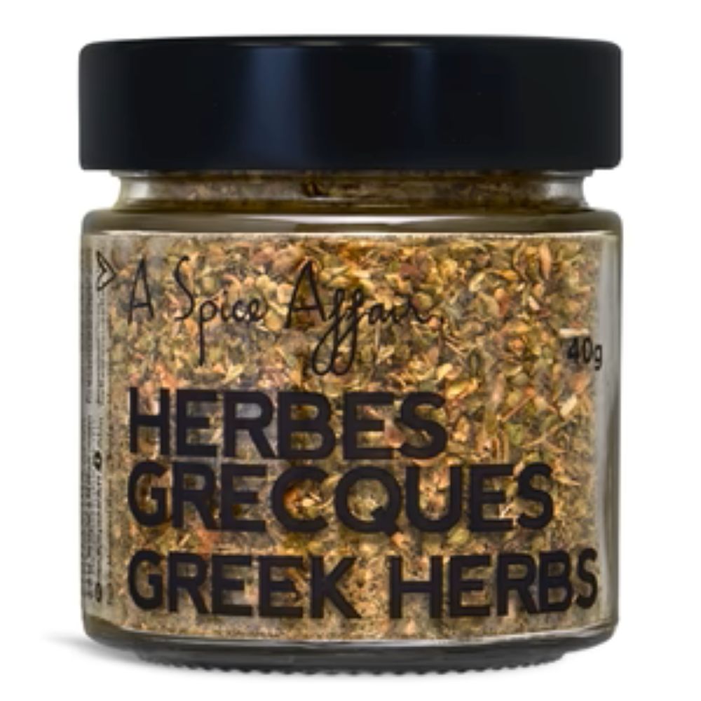 A jar of A Spice Affair Greek Herbs, featuring a black lid and a clear glass container showing the dried green and brown herb blend inside, with black text on the label.