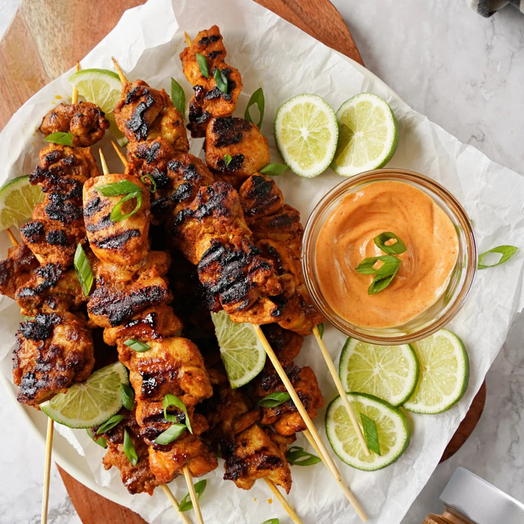 Smoked Paprika Chicken Skewers on parchment with lime slices and dipping sauce