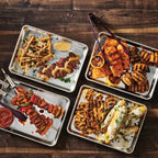 Four trays of grilled and roasted meats and vegetables on a wooden surface, seasoned with Epicure BBQ Chicken & Rib Rub