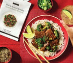Beef & Broccoli Stir Fry Seasoning package beside a bowl of saucy beef and broccoli over white rice with lime wedges and chopsticks on a red tablecloth
