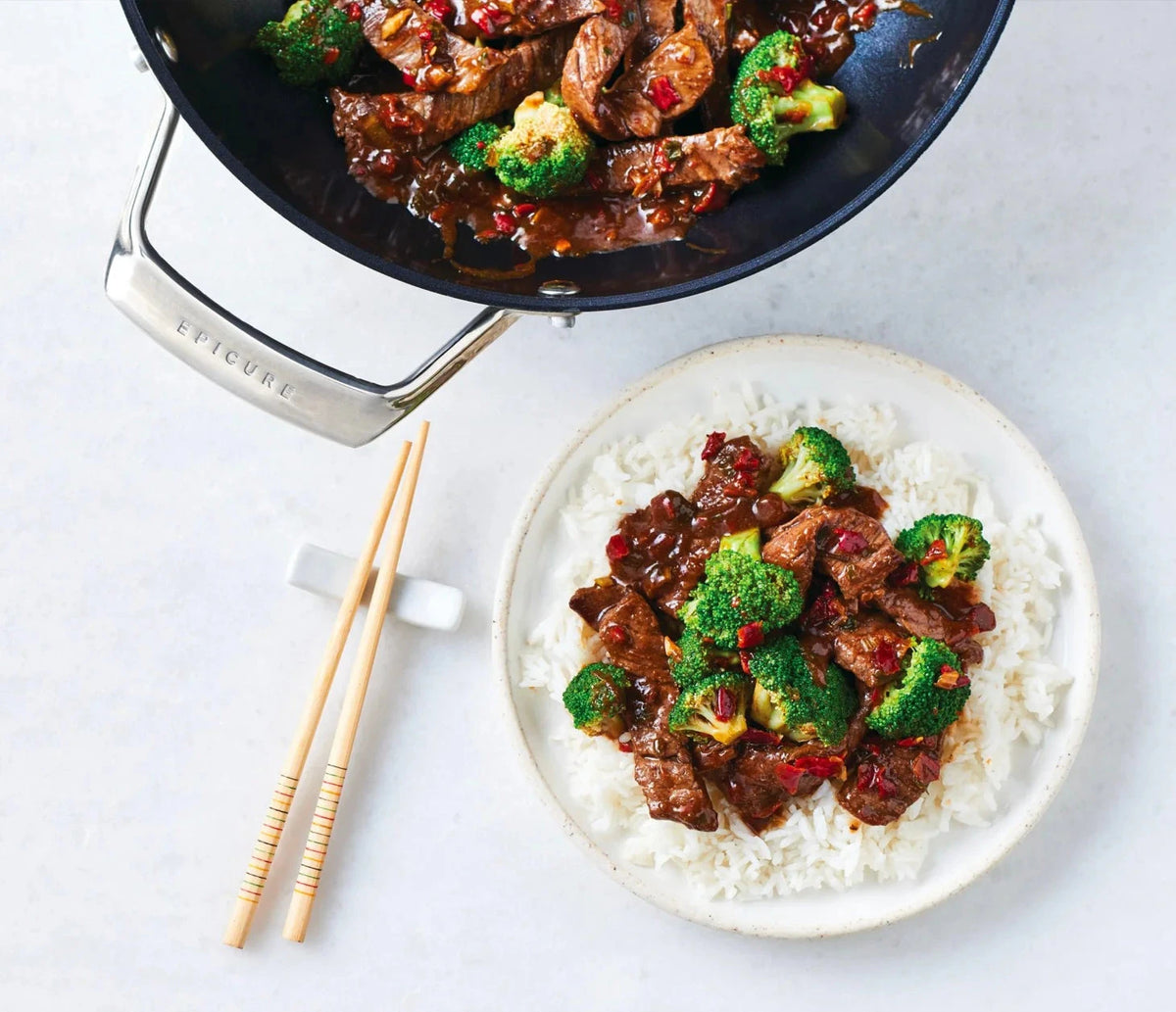 Beef & Broccoli Stir Fry Seasoning with saucy beef and broccoli served over white rice, alongside a skillet of stir fry and wooden chopsticks