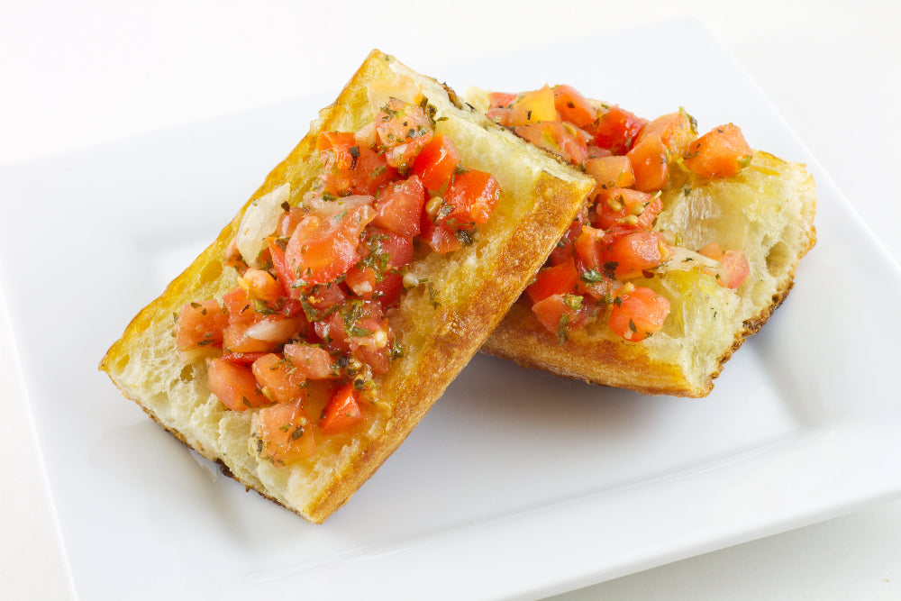 Two Italian bruschetta topped with tomato, onion and basil herb salad on a plate