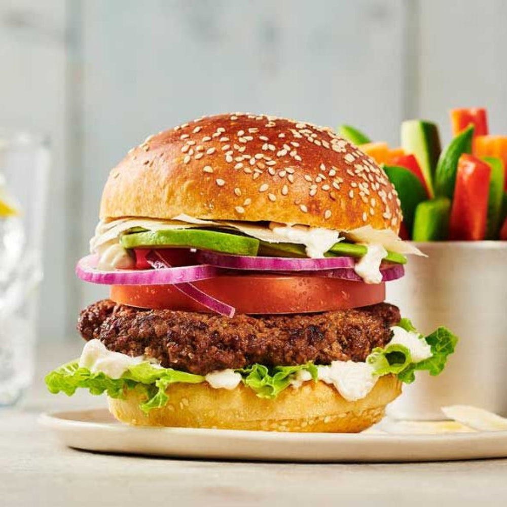 Hamburger with various toppings on a plate with a side of vegetables
