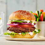 Hamburger with various toppings on a plate with a side of vegetables