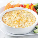 CCB Dip in a white bowl surrounded by cut vegetables on a white platter on a white background