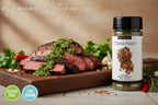 Steak with chimichurri sauce and a bottle of Epicure Chimichurri seasoning on a wooden board.