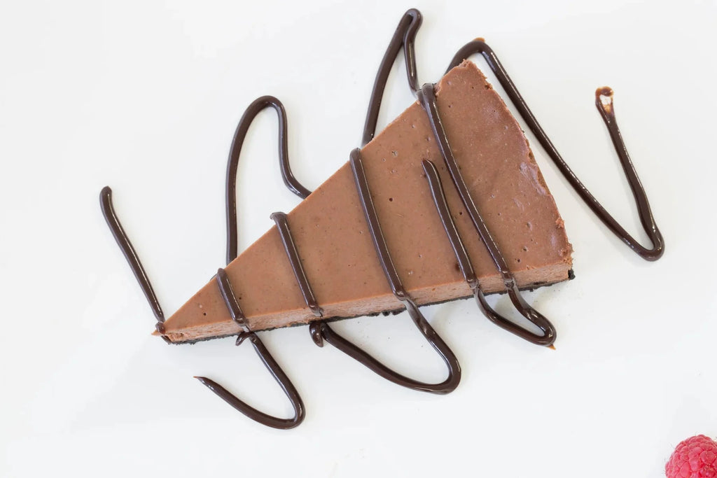 Chocolate Velvet Cheesecake slice topped with rich chocolate drizzle on a white plate with a fresh raspberry garnish‑