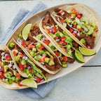 Platter of tacos with various toppings on a wooden surface