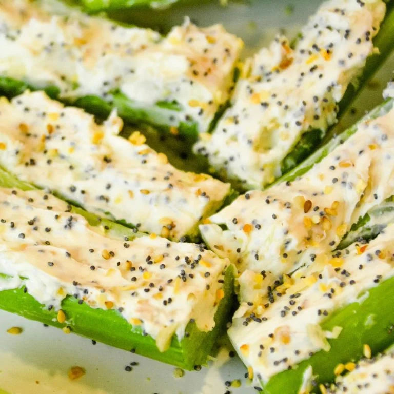 Everything Bagel Whole Food Topper sprinkled over creamy cheese-filled green vegetable pieces arranged on a plate with sesame and poppy seeds visible
