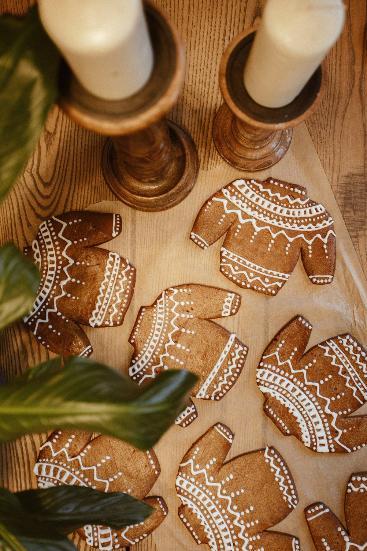 Gingerbread cookies shaped like people with sweater designs on a wooden surface.