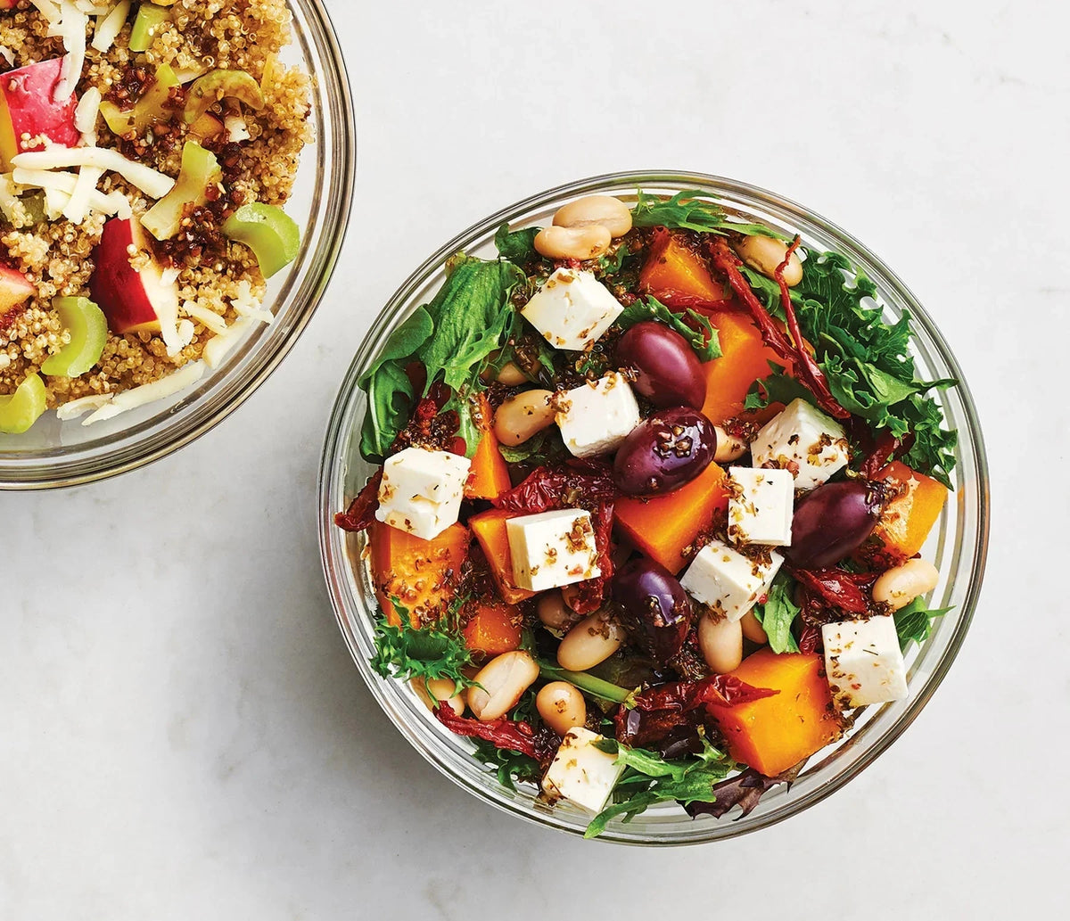 Two glass bowls filled with a colorful salad on a light gray background