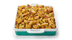 A square baking dish filled with stuffing, photographed on a clean white background. The dish has a white top and handle area with a teal-green base.