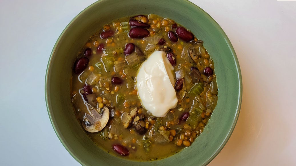 Lentil stew prepared with Epicure Herb & Mushroom Hot Dip Mix in a green bowl on a white background