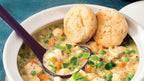 White Bowl of chicken stew with biscuits and vegetables on a blue background