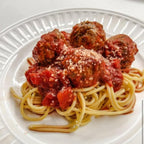 A white plate of spaghetti and meatballs on a white background