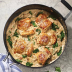 Skillet with creamy chicken and spinach dish on a gray surface