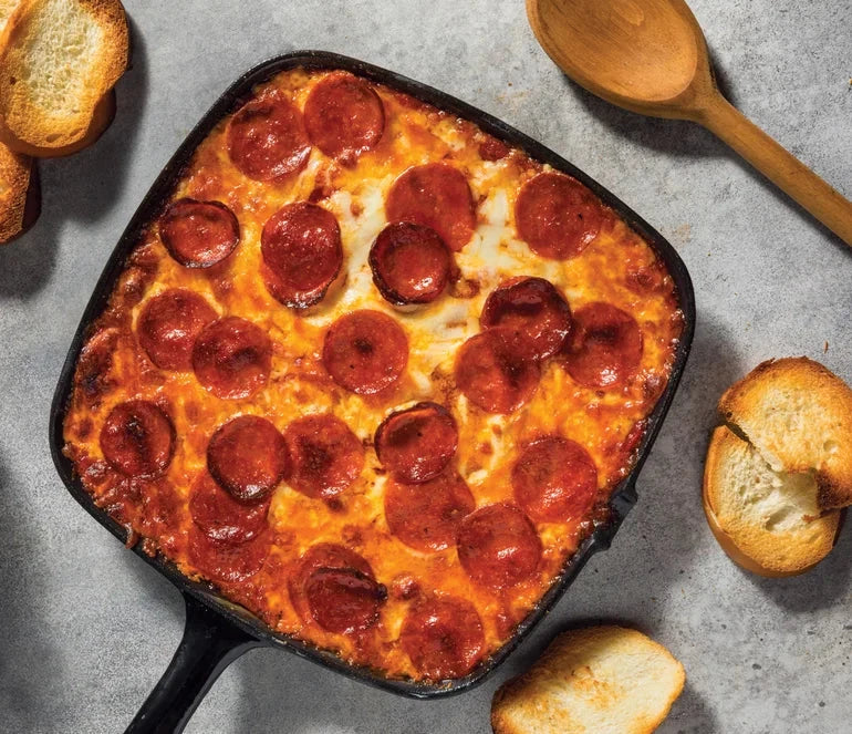 Pizza Hot Dip in a skillet with bread slices on a gray surface