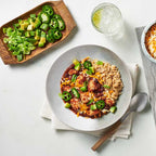 Chicken Ranchero Skillet with jalapeños, avocado and scallions, served on a white table with side dishes and utensils