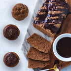 Banana bread with slices, a loaf, and chocolate-dipped cookies on a marble surface.