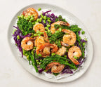Plated dish of shrimp with vegetables on a white background