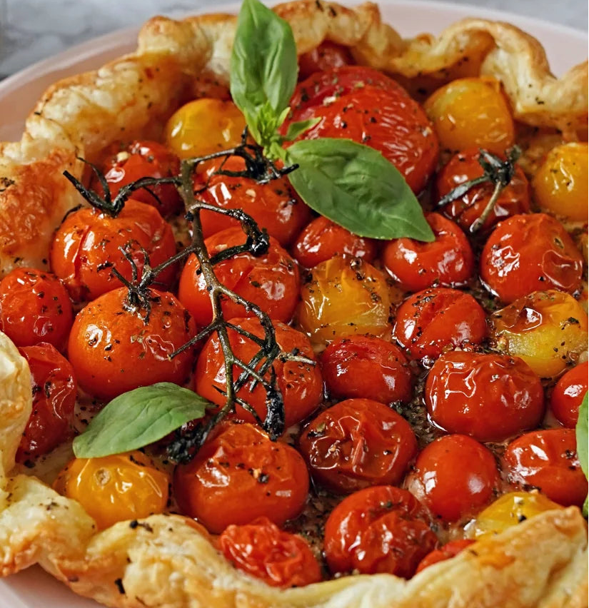 A baked tomato tart with golden flaky pastry crust, glossy roasted cherry tomatoes in red and yellow sprinkled with A Spice Affair Tuscan Infusion Seasoning.